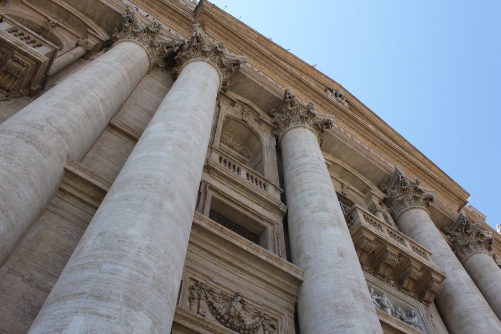 Looking up at the classical stone columns and facade of a large historic building